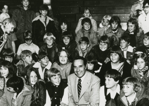 Children and a man pose for a photograph in a gymnasium.